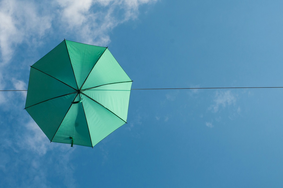Green umbrella against a blue sky with white cloud signifiying building resilience
