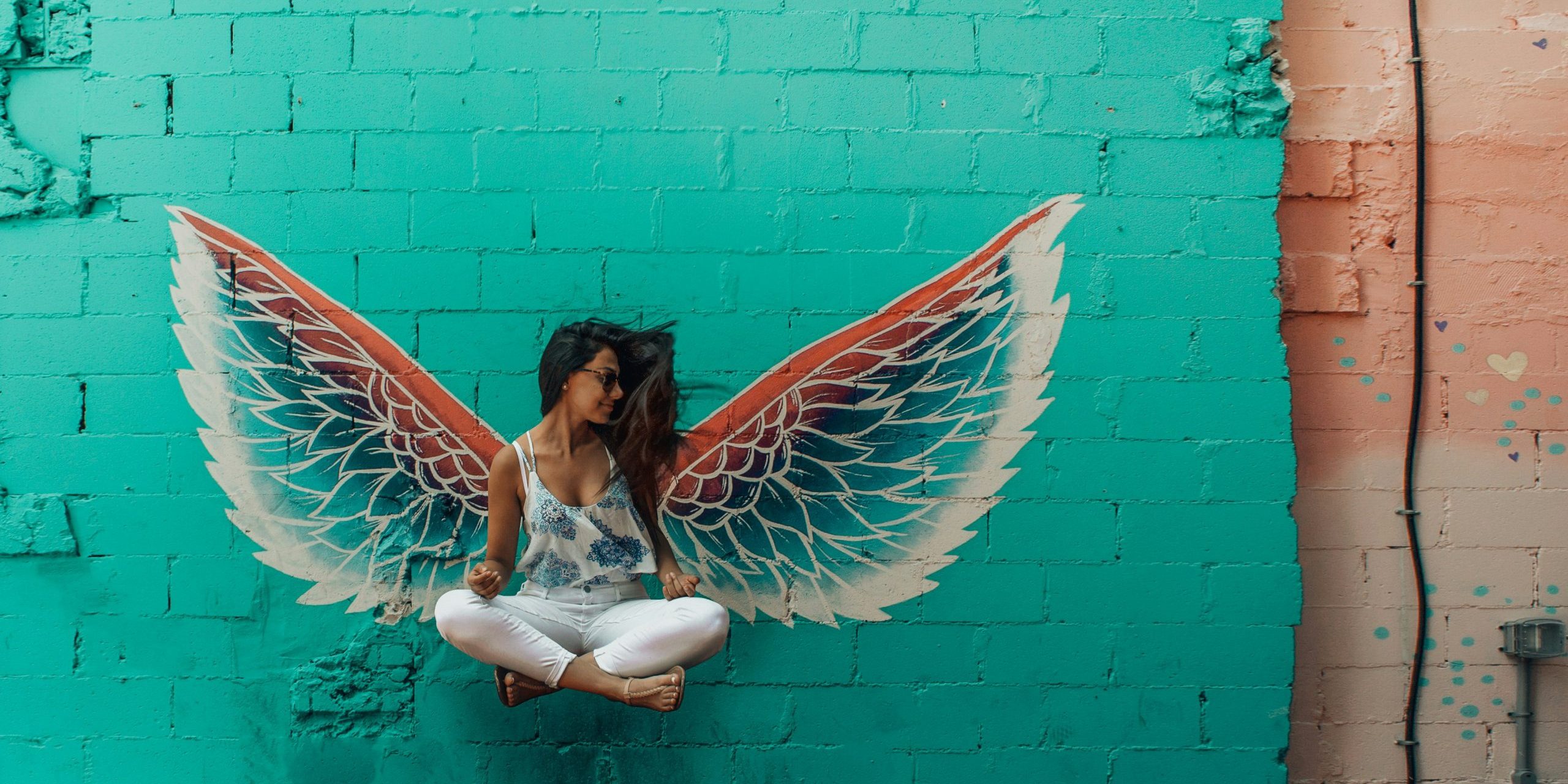 designecologist-P1sMtXL4jow-unsplash woman with coloured wings floating against turquoise wall coaching challenges your decisions