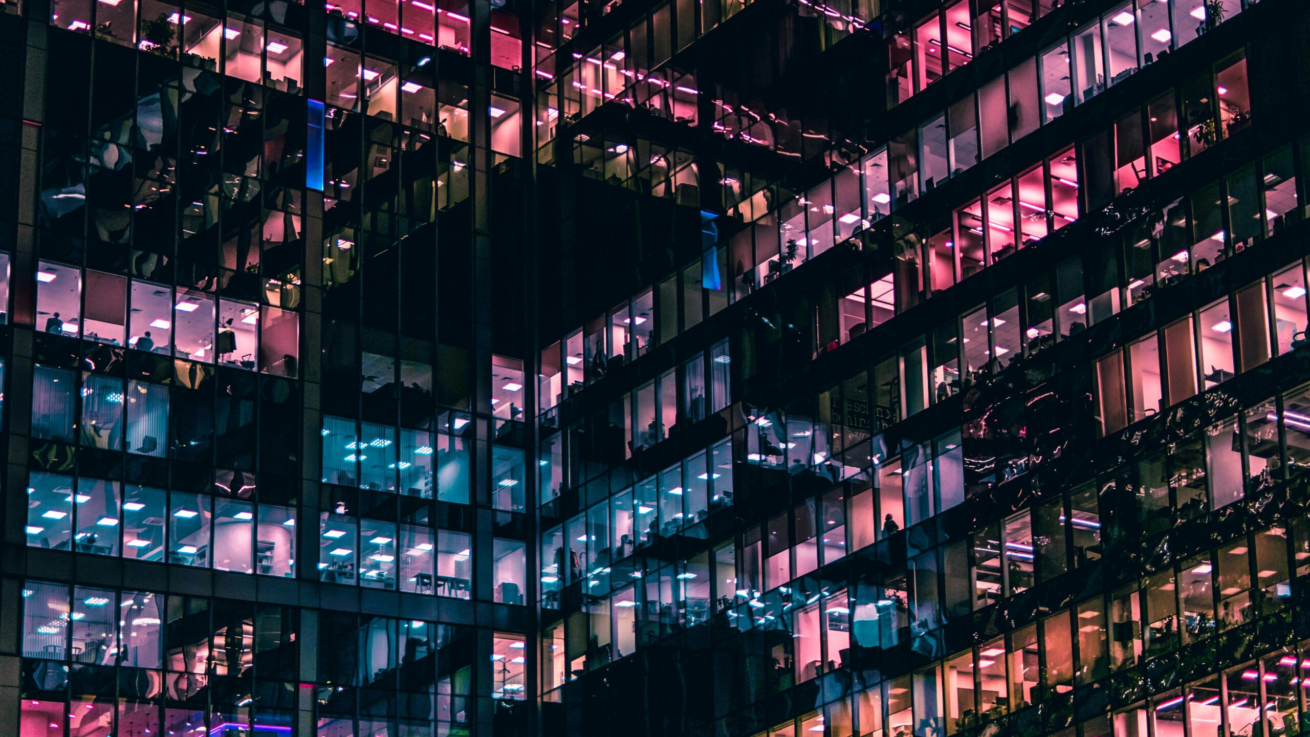image shows office block windows at night with different colours reflected, signifying that leadership coaching is multi-faceted